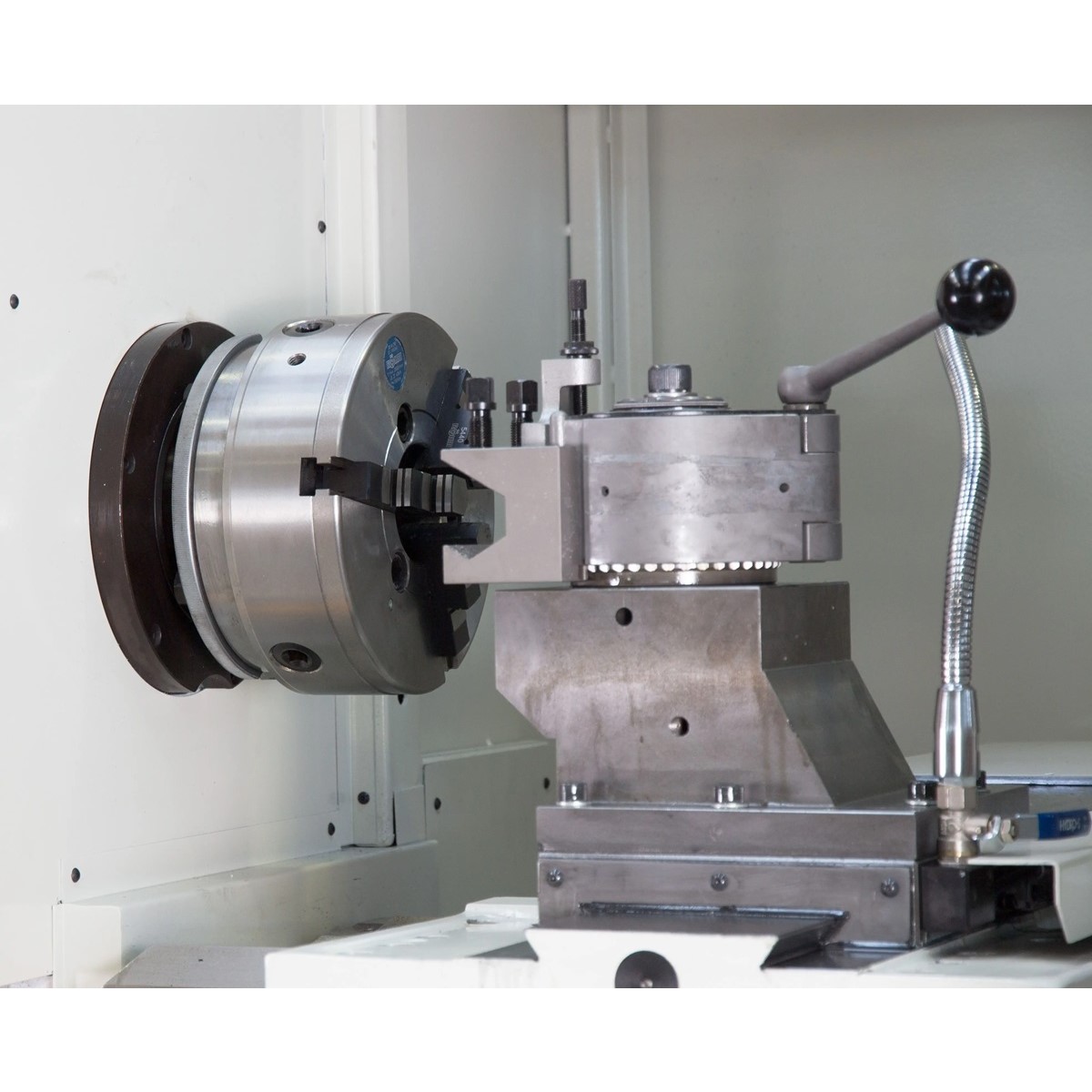 Arbeitsbereich der ELMAG PREMIUM LT 580 CNC-Drehmaschine mit Drehfutter, Werkzeughalter und Kühlmittelschlauch.
