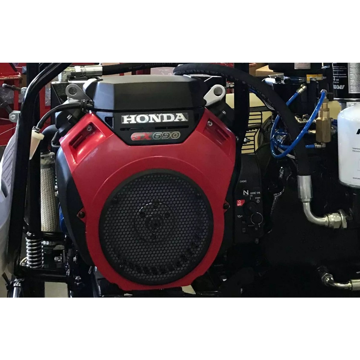 Detailansicht des eingebauten Honda GX690 Motors mit rotem Gehäuse, Lüftergitter, Schläuchen und Leitungen.