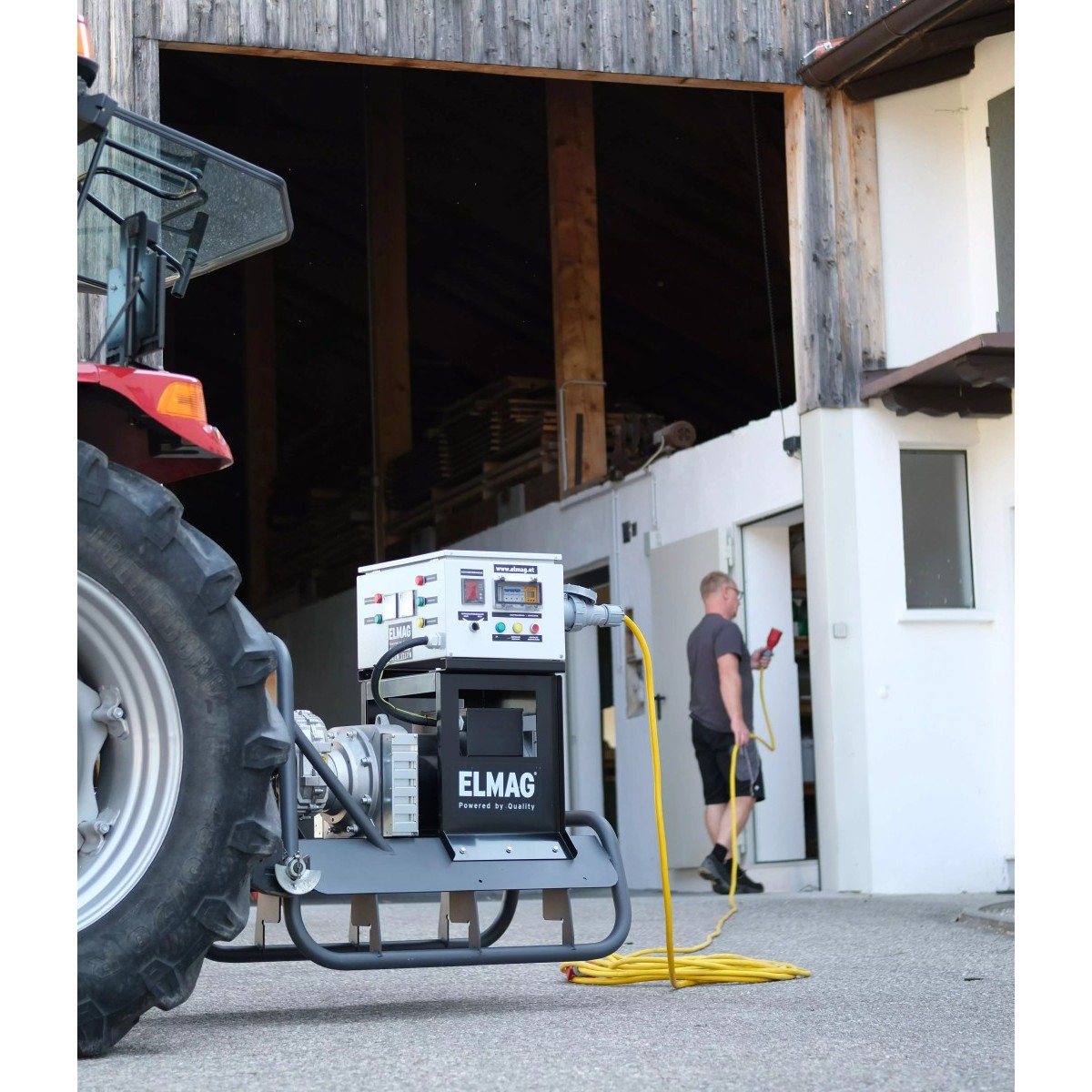 Stromaggregat am Traktor, Kabel führt zu einem Mann im Gebäude; Hofszene mit Scheune.