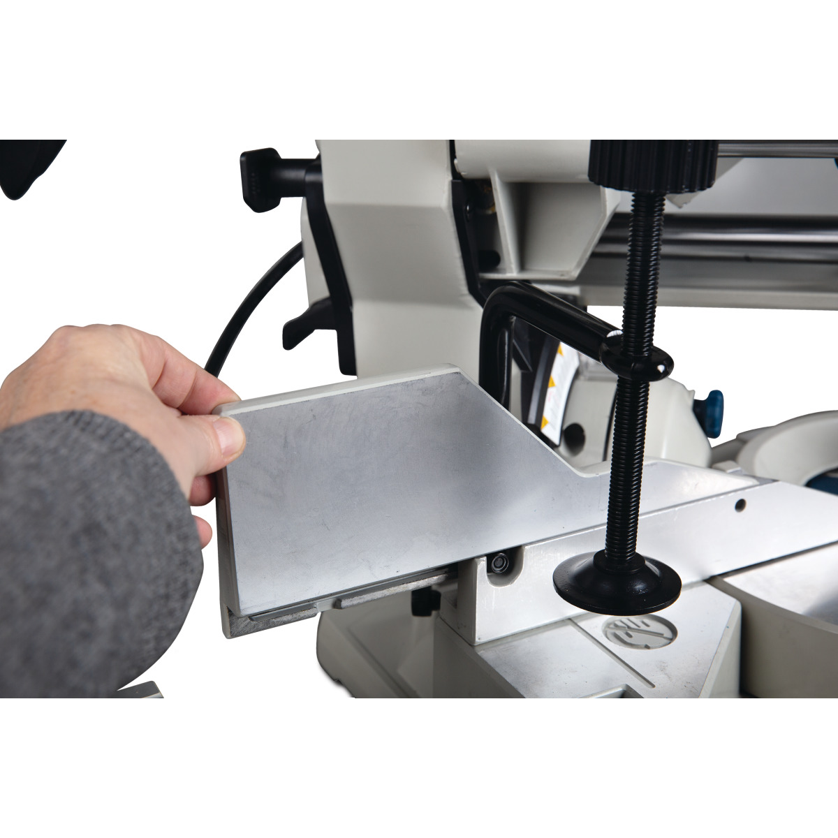 Hand setzt Metallanschlag an der Gehrungssäge ein, Detailaufnahme.