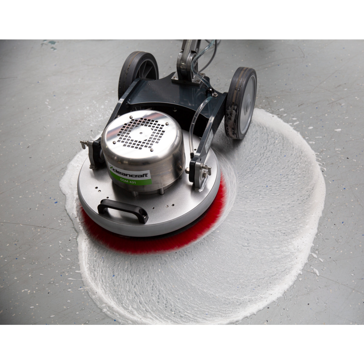 Orbital-Einscheibenmaschine OSM 431 Bodenreinigungsmaschine mit roter Bürste verteilt Reinigungsschaum auf grauem Industrieboden.