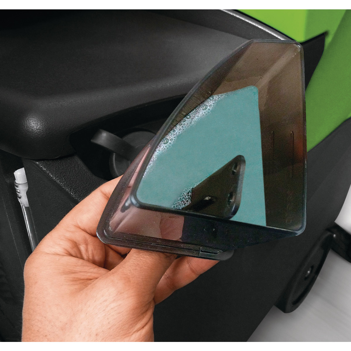 Aufsitzscheuersaugmaschine ASSM 560 Hand hält transparenten Wassertankdeckel mit sichtbaren Seifenblasen.