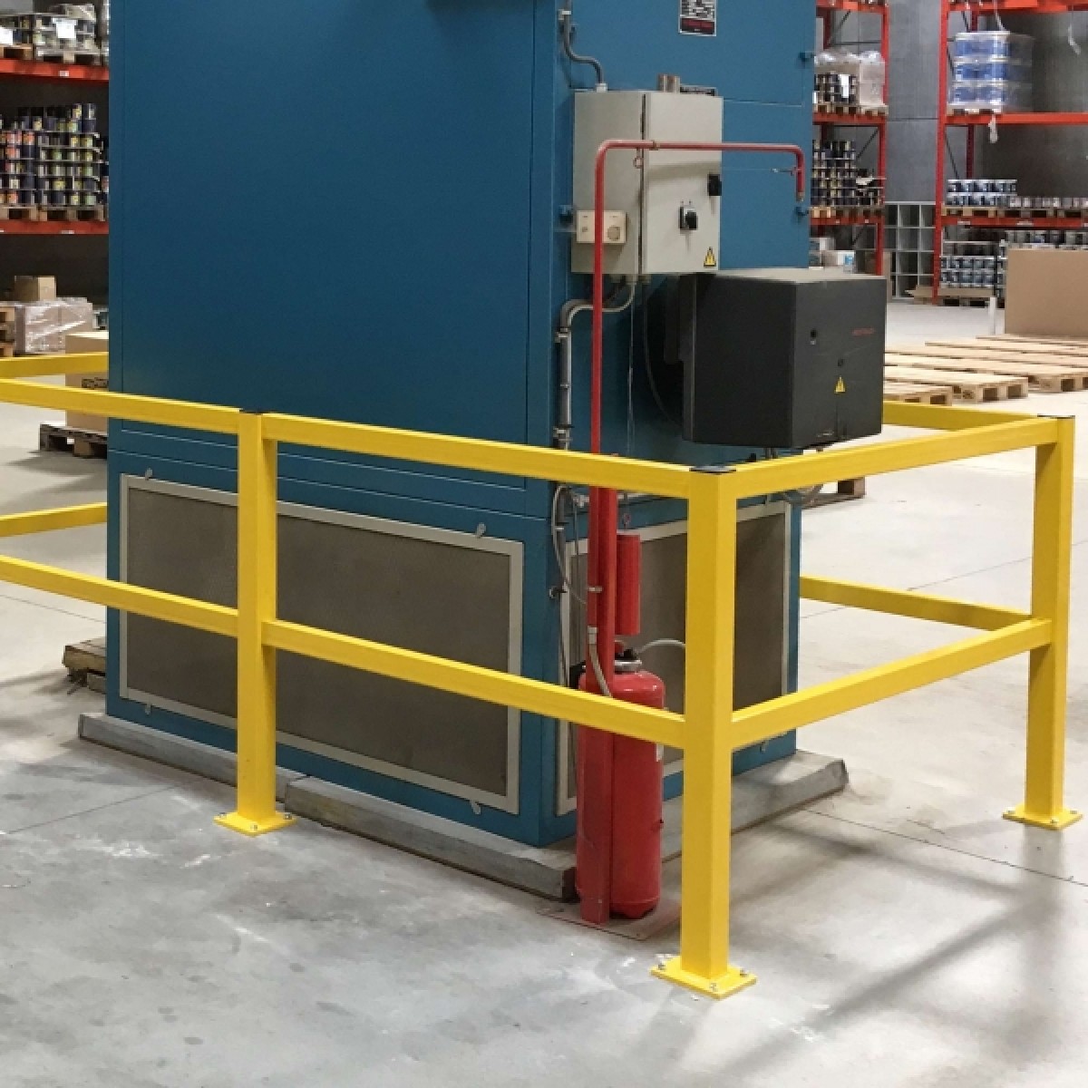 BLACK BULL Rammschutz-Geländer S-Line - Querbalken Gelbes Schutzgeländer vor einer blauen Maschine; daneben Schaltschrank und roter Feuerlöscher im Lager.