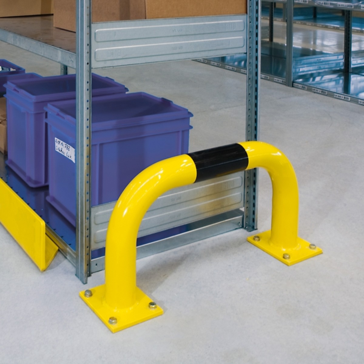 Rammschutz-Bügel - Ø 76 Foto: Niedriger gelber Schutzbügel mit schwarzem Streifen vor einem Metallregal mit blauen Kunststoffboxen in Lagerhalle.