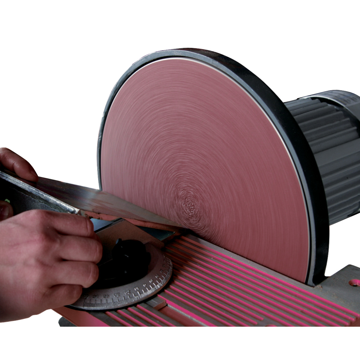 Tellerschleifmaschine OPTIgrind TS 305 Hand führt ein Metallteil an eine rotierende Schleifscheibe auf dem verstellbaren Arbeitstisch eines Tellerschleifers.